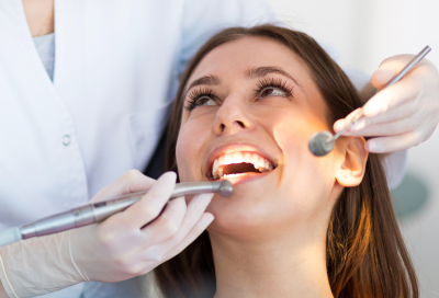 Woman smiling while getting her teeth worked on at the dentist, representing benefits of root canal treatment