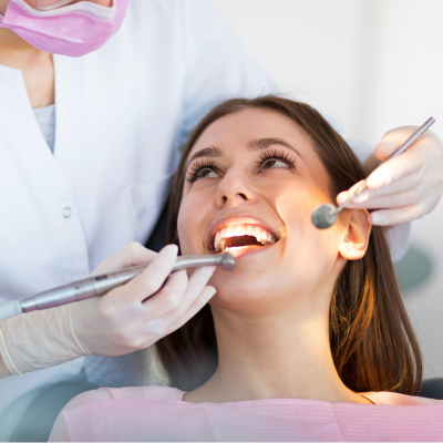 Woman smiling while getting her teeth worked on at the dentist, representing benefits of root canal treatment