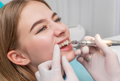 Female patient getting her teeth cleaned at the dentist, representing deep cleaning vs regular cleaning
