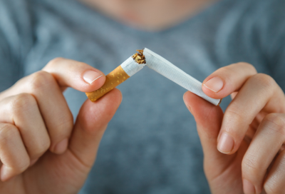 Person snapping a cigarette in two, representing how smoking affects oral health