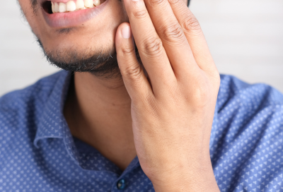 Person holding their jaw in pain, representing how to treat sensitive teeth