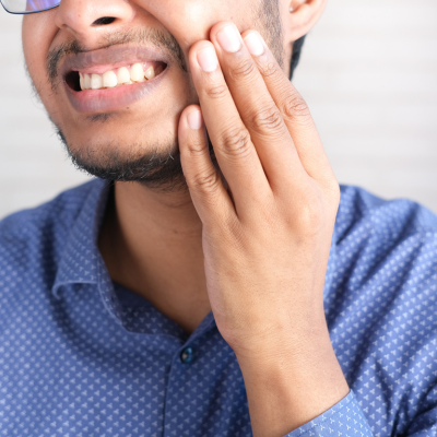 Person holding their jaw in pain, representing how to treat sensitive teeth