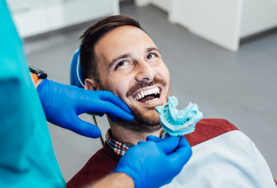 Man smiling while receiving dental work on his teeth, representing comprehensive dental services