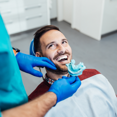 Man smiling while receiving dental work on his teeth, representing comprehensive dental services
