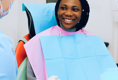 Woman smiling while sitting in a dental chair and talking to a team member, representing medical clearance for dental work