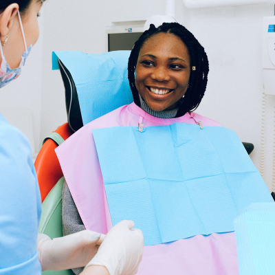 Woman smiling while sitting in a dental chair and talking to a team member, representing medical clearance for dental work