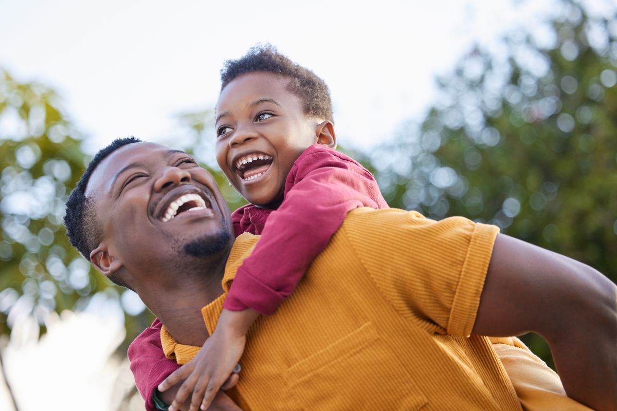 Expert-dental-care-center-near-brook-valley Father giving his young son a piggyback ride in a garden, representing trusted, top-rated family dentistry near brook valley