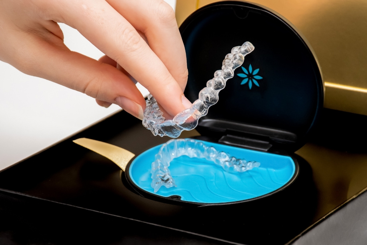 The-dental-care-center-invisalign-benefits Hand placing clear invisalign aligners into a cleaning case, highlighting easy care and maintenance.