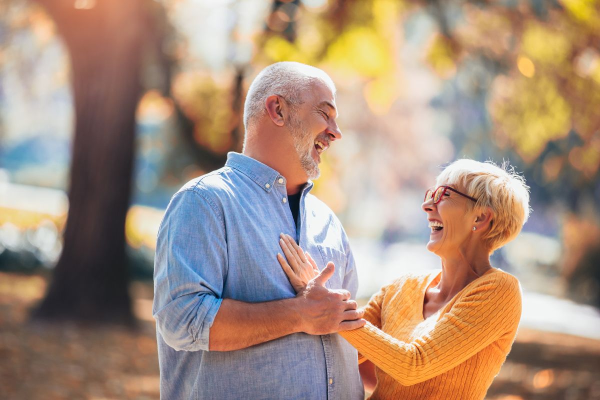 Top-rated-full-mouth-restorations-eastern-north-carolina Couple smiling outdoors after full-mouth restoration dental treatment.