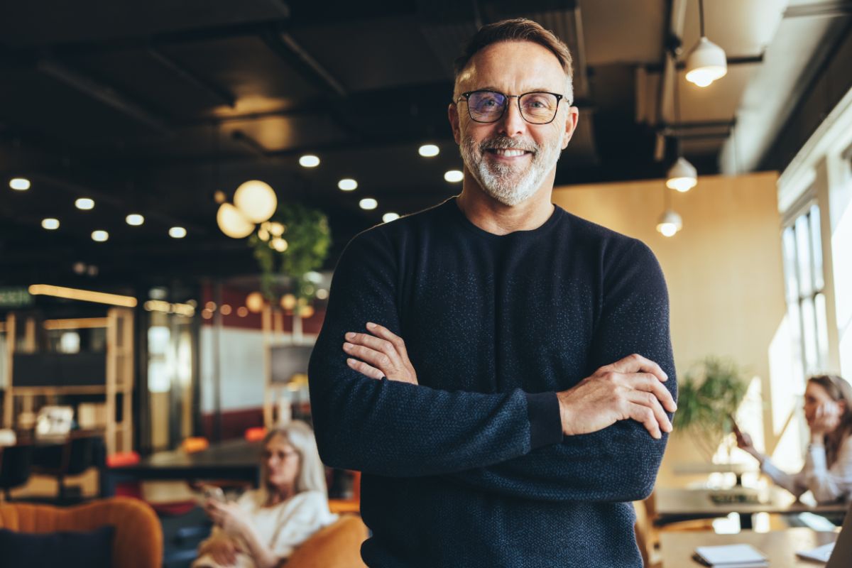 Top-rated-smile-club-dental-care-center Mature businessman standing confidently in a co-working space, representing smile club membership at the dental care center