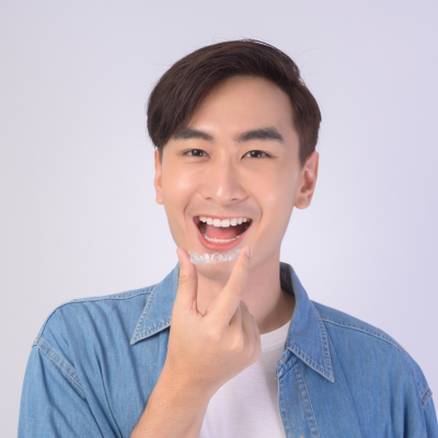 Faqs about invisalign 3 Man smiling while holding invisalign aligners up to his mouth, representing faqs about invisalign