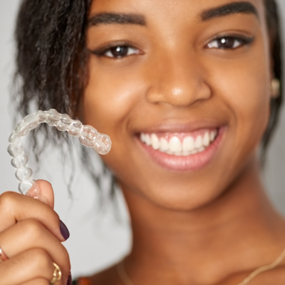 What is invisalign? 5 Teenage girl smiling and holding invisalign aligner, representing what is invisalign?